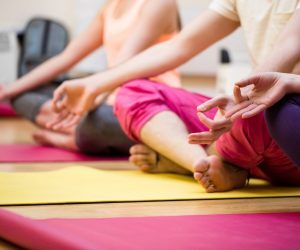 Group of people sitting in lotus position in the fitness studio